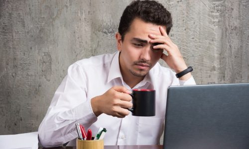 hombre-negocios-taza-te-cansado-escritorio-oficina-foto-alta-calidad_114579-28328